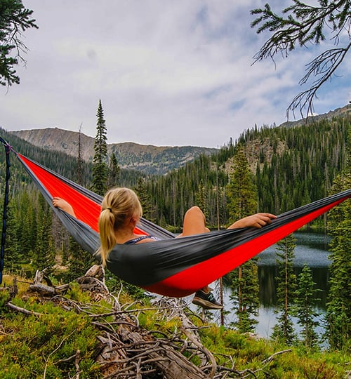 A woman laying in a hammock on top of a hill.